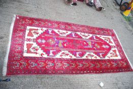 An Iranian hand woven Rug with stylized peacocks in red and cream, 86" x 43".