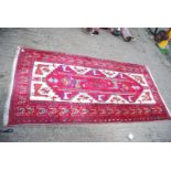 An Iranian hand woven Rug with stylized peacocks in red and cream, 86" x 43".