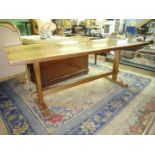 A contemporary Oak refectory design Dining Table standing on end supports with peg-retained central