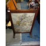 An Oak framed Fire screen having a fluted top rail and with an inset tapestry depicting a thatched