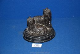 A cast sculpture on black marble base of two long haired Yorkie type dogs, indistinctly signed,