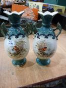 A pair of two handled vases with winter scenes to the front and floral design to the back.