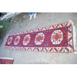 A bordered patterned and fringed Runner in red, blue and cream with five hexagons down the centre,