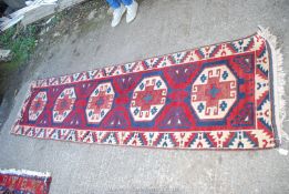 A bordered patterned and fringed Runner in red, blue and cream with five hexagons down the centre,
