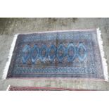 A small bordered patterned and fringed Rug in light blue and brown with hexagons down the centre,
