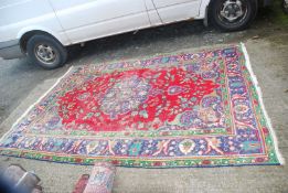 A large bordered patterned and fringed Rug in red, purple and green ground with flower vases design,