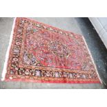 A bordered patterned and fringed Rug in terracotta and orange with large centrepiece,