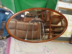 An oval mirror with marquetry surround. 35" x 19 1/2".