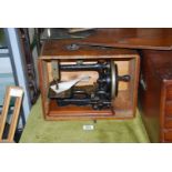 A small wooden cased hand Sewing Machine with mother of pearl detail to base, serial no.