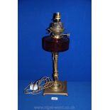 A Brass Oil Lamp with cranberry glass oil reservoir, converted to electric,
