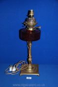 A Brass Oil Lamp with cranberry glass oil reservoir, converted to electric,