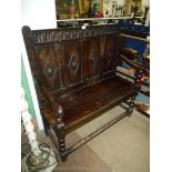 A peg-joyned Oak Settle having four panelled back rest with fluted and carved top rail,