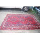 A bordered patterned and fringed Rug in navy and red with three diamonds down the centre and