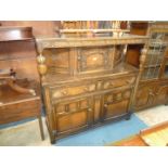 A dark Oak Priory style contemporary Court Cupboard having carved details including a fluted frieze,