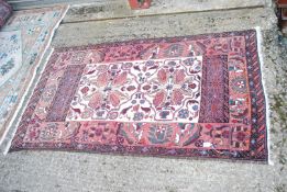 A bordered patterned and fringed Rug in terracotta and burgundy with cream centre and swan detail,