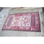 A bordered patterned and fringed Rug in terracotta and burgundy with cream centre and swan detail,