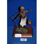 A cold painted bronze figure of a Lady carrying water (one water carrier missing) with wooden base,