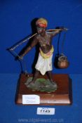 A cold painted bronze figure of a Lady carrying water (one water carrier missing) with wooden base,