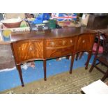 A contemporary cross-banded Mahogany serpentine fronted Sideboard standing on six tapering square