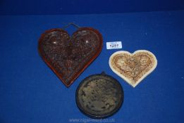 Three old wax plaques; two being heart shaped in floral pattern and one circular.