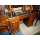 A compact Mahogany Kneehole Desk having a frieze drawer and flanked by a drawer and a cupboard to