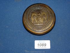 A horn circular snuff box, the central design within a laurel wreath and the figure of Flora,
