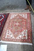 A bordered patterned and fringed Rug in brown and cream geometric pattern with pink border,