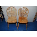 A pair of light-wood wheel-back side chairs.