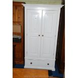 A white painted wood wardrobe with lower drawer and having turned knob handles.