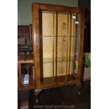 A glazed fronted Walnut finished display cabinet with two glass shelves and standing on brief