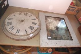 A large metal clock face in frame and a wooden framed mirror.