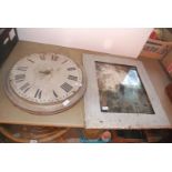 A large metal clock face in frame and a wooden framed mirror.