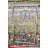 A Metal gate decorated with a steering wheel and wheel 47 1/2" high x 32" wide.