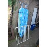 An ironing board and cover and a child's safety gate.