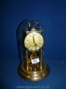 A brass coloured Kein anniversary clock with glass dome, 11" tall.