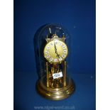 A brass coloured Kein anniversary clock with glass dome, 11" tall.