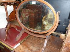 An oval Mahogany swing mirror having bevelled glass, frame requires a small repair/gluing,