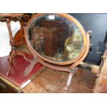 An oval Mahogany swing mirror having bevelled glass, frame requires a small repair/gluing,