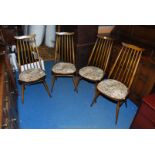 A set of four "Ercol" dark-wood stick back Dining Chairs having "H" stretchers and solid wood seats.