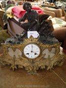 A metal cased Mantel Clock having a part gold and part black finished case surmounted by a kneeling