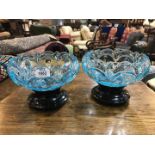 A pair of blue glass shaped Bowls, 9 1/2'' diameter standing on black glass stands,