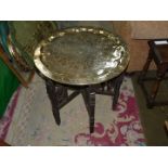 A circular engraved brass Benares table top with original carved wooden base c. 1900.