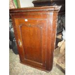 A Georgian dark Oak wall-hanging Corner Cupboard having a recessed shaped panelled door,