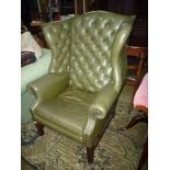 A contemporary wing Fireside Chair having buttoned back rest and upholstered in green leather,