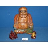 A carved wood and two resin laughing Buddha's, one with gilt detail.