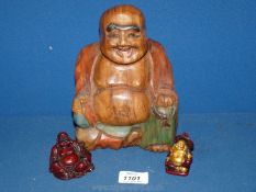 A carved wood and two resin laughing Buddha's, one with gilt detail.