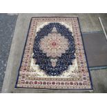 A large border patterned and fringed rug with large central flower in cream with dark blue surround