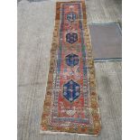 A long runner with brown floral border and four diamond shapes to the centre panel, very worn,