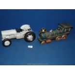 A vintage tin plate battery operated train and grey metal toy tractor.