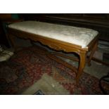A Satinwood show framed two seater Stool having carved shell and scroll detail to the friezes,